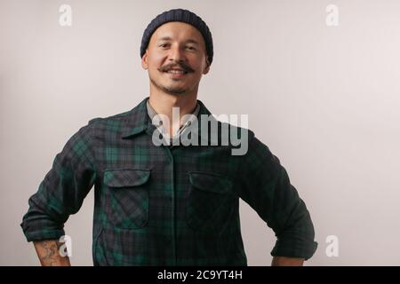 Portrait of kind cheerful smart professional friendly expert handsome handyman wearing knitted hat standing isolated on gray background copyspace Stock Photo