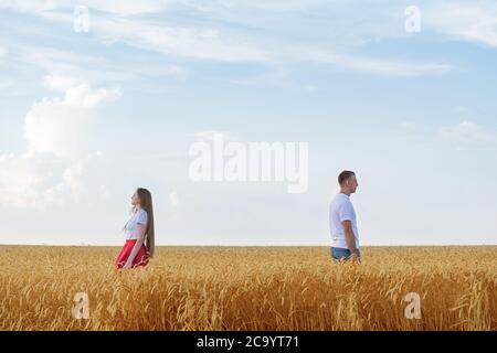 couple standing back to each other in wheat field. Divorce. Stock Photo