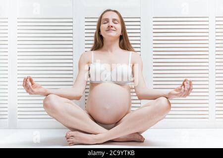 Pregnant young woman meditating in Lotus position. Yoga for pregnancy. Stock Photo
