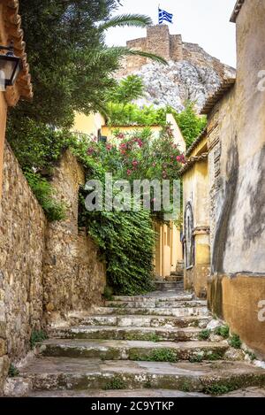 Plaka district in Athens, Greece. Narrow street with vintage stairs and old houses, traditional alley overlooking famous Acropolis of Athens. Plaka is Stock Photo