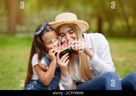 Joyful Mother And Little Daughter Eating Watermelon Enjoying Picnic Outside Stock Photo