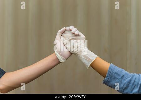 Handshake with white medical gloves, rubber glove for professional medical safety and hygiene protection from Coronavirus disease. Healthcare and medi Stock Photo