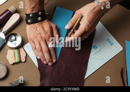 Closeup male hands working with leather using crafting DIY tools. Small business and shoe and leather accessories manufacturing Concept Stock Photo