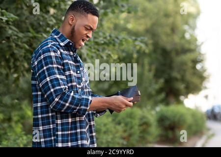 Shocked african guy looking at his empty purse Stock Photo