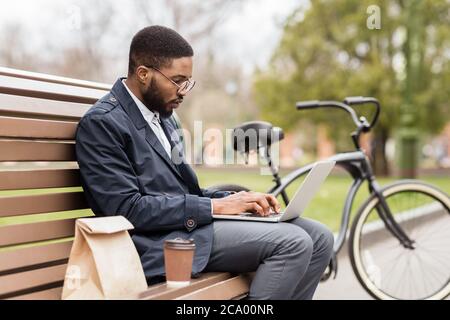 Handsome manager working on laptop in park in spring Stock Photo