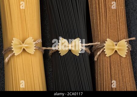 Three bunches of different types of Italian spaghetti. Black, brown and yellow spaghetti. Close up. Stock Photo