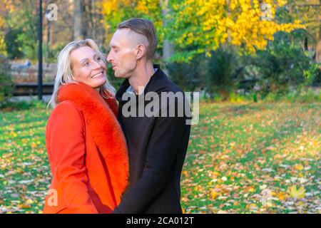 Middle-aged couple in autumn park. Smiling pair on colorful fall background. Lovely couple on autumn trees background. Couple having fun in multicolor Stock Photo