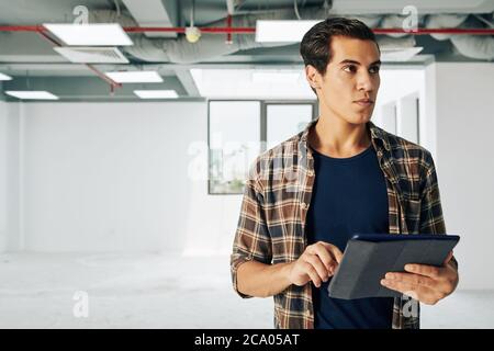 Young real estate manager visiting new building and filling information in database on tablet computer Stock Photo