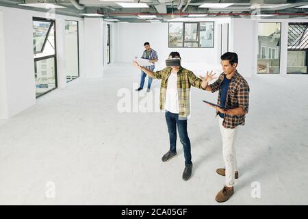 Young developers testing new virtual reality application in empty room of buildng under construction Stock Photo