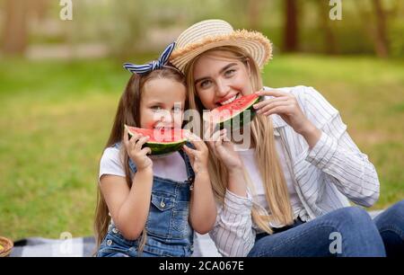 Woman And Her Little Daughter Eating Watermelon In Countryside Stock Photo