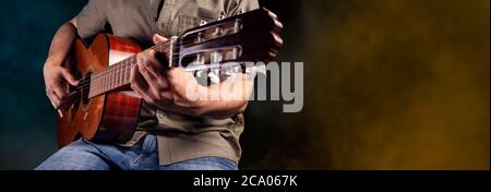 Classical guitarist plays piece of music. Men musician plays classical guitar. Guitarist isolated on black. Beautifull woodem acoustic instrument clos Stock Photo