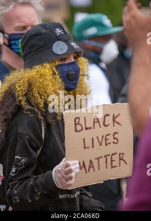 Woman protester, with yellow hair, wearing a mask and hat holds up a 'BLACK LIVES MATTER' sign at the London Hyde park protest. UK Stock Photo
