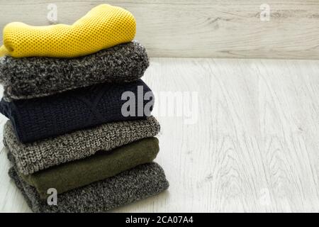 Stack of sweaters on a wooden background. Fashionable concept. Stock Photo