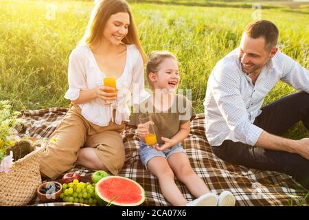 Laughing family drinking orange juice from glasses Stock Photo