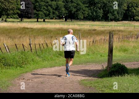 Senior retired retiree male,man jogging,exercising in a UK country park Stock Photo