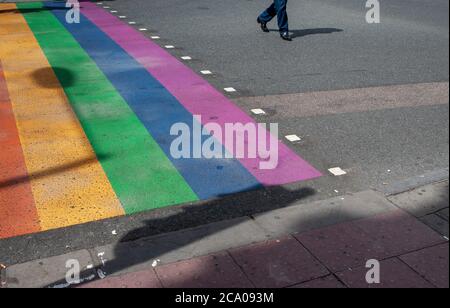 Person walking across a rainbow coloured pedestrian crossing in Camden, London, England, U.K. Stock Photo
