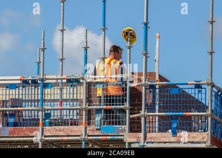 Builders working in Tarleton, Lancashire.  UK Weather. Hot summer sun for new build housing estate development in the new Persimmon housing Estate in Douglas Gardens. A major development that may be put on hold depending on the severity of the impending recession.  Contractions are expected to be sharpest in private housing (-42 per cent), commercial and private housing repair, maintenance and improvement , these are the sectors that are most closely linked to consumer and business confidence, likely to be significantly dented by fading job security and rising unemployment. Stock Photo