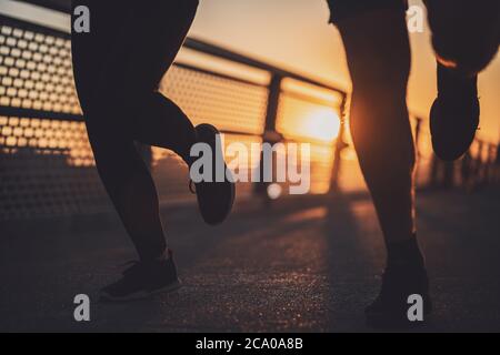 Body part silhouettes of couple who is jogging in the city in sunset. Stock Photo