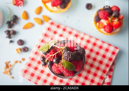 Fresh ripe organic raspberry, strawberries and black currant in tin can and small tartlet with berries. Stock Photo