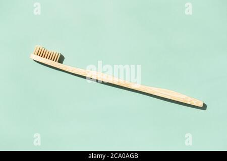 Bamboo toothbrush on mint background with copy space. Top view in sunlight. Stock Photo