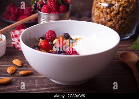 Yogurt with fresh berries, muesli oatmeal granola on the wooden table. Healthy breakfast concept Stock Photo
