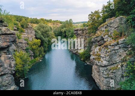 the river flows through a canyon with large stones and rocks Stock Photo