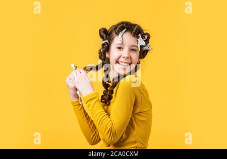 Child fashion model concept. childhood happiness. beauty and fashion. Child making hairstyle. little happy girl with curlers in hair. cute kid standin Stock Photo