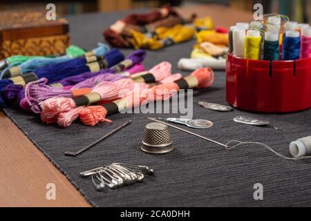 The sewing items are on the table. The thread is threaded over the needle on the thimble. Stock Photo