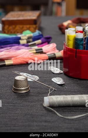 The sewing items are on the table. The thread is threaded over the needle on the thimble. Stock Photo