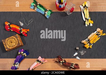 Various colored mouline threads, yarns, threads lie on the table with accessories for needlework and sewing. Place for text inside. Stock Photo
