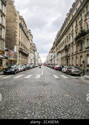 A quiet Parisian street, with building showing typical French Architecture on either side, photographed on a rainy day in Paris France Stock Photo