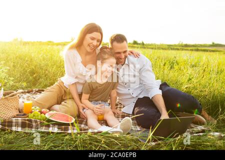 Happy family together on a picnic with personal computer