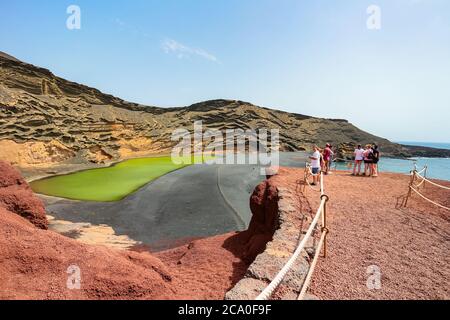 Tourists at Lago Verde (or Charco de Los Clicos) viewpoint take pictures and enjoy the uniquely colorful landscape during the coronavirus pandemic. Stock Photo