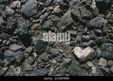 Heart shaped white stone among dark volcanic rocks background with copy space. Seen in Lanzarote, Canary Islands, Spain. Stock Photo
