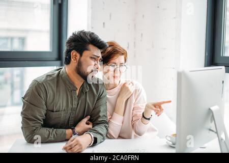 worried business man and woman colleagues looking at computer trying to solve problems in office Stock Photo