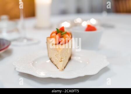 Fresh strawberry cheesecake on a ceramic plate on a white festive table Stock Photo