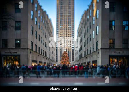 Big Christmas tree stands among the Rockefeller Center buildings under the blue sky. Christmas tree is decorated with 50,000 LED lights and glows in t Stock Photo