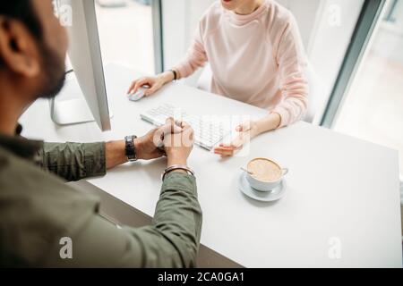 Portrait of investment advisor businesswoman sitting at computer and consulting with young professional man or client Stock Photo