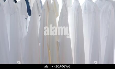 white men's shirts hang on the shoulders in the closet Stock Photo