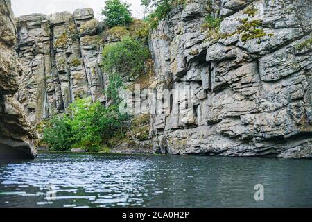 sheer cliff with large rocks above the water Stock Photo