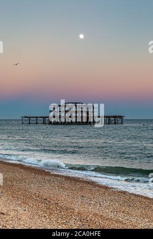 Brighton's West Pier at sunset, with a full moon overhead Stock Photo