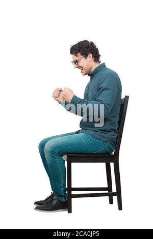 Side view full length hysterical and passionate businessman sitting on chair, keeps fists tight, shouting and screaming, isolated on white background. Stock Photo