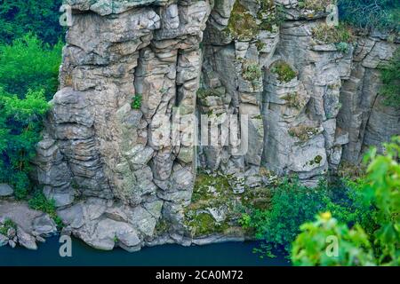 sheer cliff with large rocks above the water Stock Photo