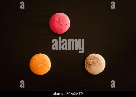 Three multicolored macarons on a black background Stock Photo