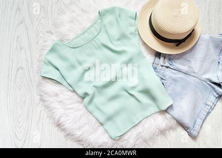 Mint green t-shirt, blue jeans and straw hat on a white fur. Fashion collage Stock Photo