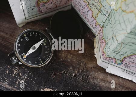Compass lying on a wooden table next to the map Stock Photo