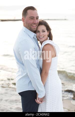romantic couple embracing and laughing at ocean Stock Photo