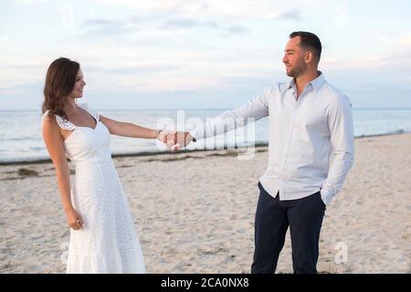 romantic couple holding hands and looking at each other at beach Stock Photo