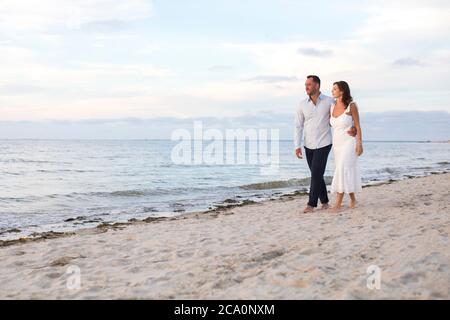 romantic couple walking arm in arm at beach Stock Photo