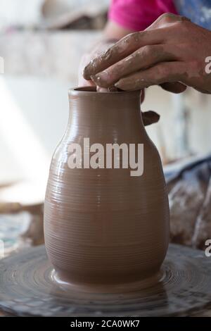 Potter hands making in clay on pottery wheel. Potter makes on the pottery wheel clay pot. Stock Photo